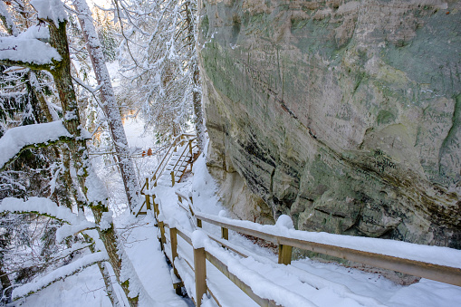 Tourist trail in winter. Wooden stairs by sandstone cliffs. The rock landscape of Sietinezis in the Gauja National Park.