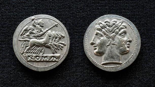 Ancient Roman coin showing Jupiter on horses and god Janus, 225-214 BC Ancient Roman coin showing Jupiter on horses and god Janus, 225-214 BC. Old rare money, silver didrachm isolated on dark background, macro. Concept of Rome, valuable coin, civilization and history. janus head stock pictures, royalty-free photos & images