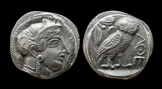 Ancient Greek coin showing goddess Athena and owl. Old rare money of Athens, silver tetradrachm isolated on black background, macro. Theme of Greece, valuable coin, civilization, culture and history
