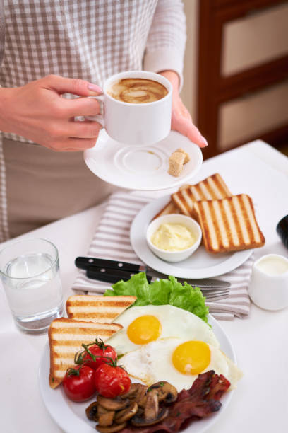 istock Fried eggs, bacon, tomato, toasted bread in white ceramic plate and cup of coffee 1448225580