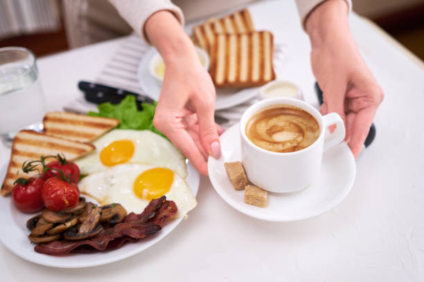 istock Fried eggs, bacon, tomato, toasted bread in white ceramic plate and cup of coffee 1448225583