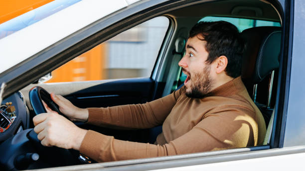 istock Young guy man looks ahead shouts joyful surprised while holding the steering wheel. 1448225880