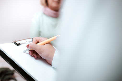 Closeup shot of a doctor writing notes during a consultation with a patient, Health insurance concept, Doctor filling out patient medical documents