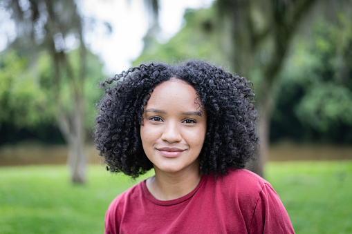 Environmental portrait of a beautiful young black woman looking at camera in a park