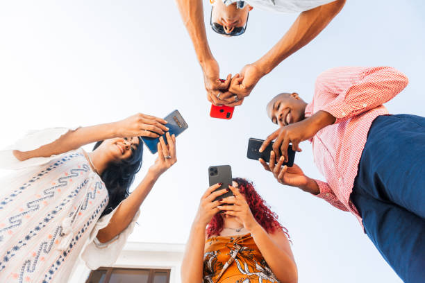istock Group of four friends together using smartphones. 1448235026