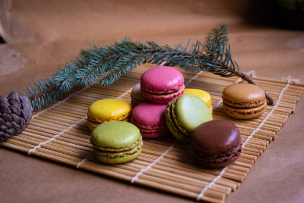 istock multi-colored macarons lie on a bamboo mat - Makisu with a branch of a Christmas tree and a cone and a blurred light brown background 1448236782