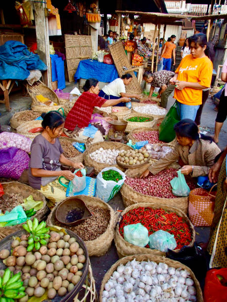 Vertical closeup photo of Balinese people buying and selling a variety of foods and ceremonial offerings at the daily morning traditional Market in the main street of Ubud. Bali, Indonesia. 7th October, 2007.