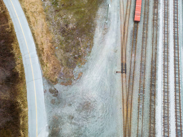 istock Country Road and Train Tracks Running Between a Grassy Meadow and A Deciduous Forest in Autumn Arial Photo 1448243039