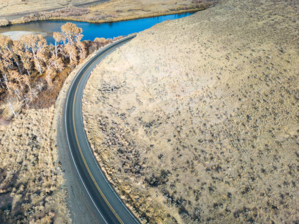 istock Road Winding Through Golden Hills with Shrub and Tree Vegetation Along River 1448243119