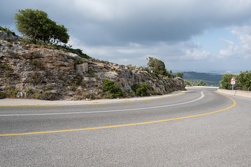 Winding empty road through the north of Israel in Golan mountains. Road curves into the rock landscape.