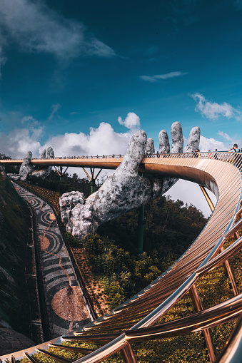 Da Nang city, Vietnam - November  18, 2022:Tourists walk on the Golden Bridge in Ba Na Hills, supported by a pair of giant hands. The bridge located 1,400 meters above sea level with hill scenery