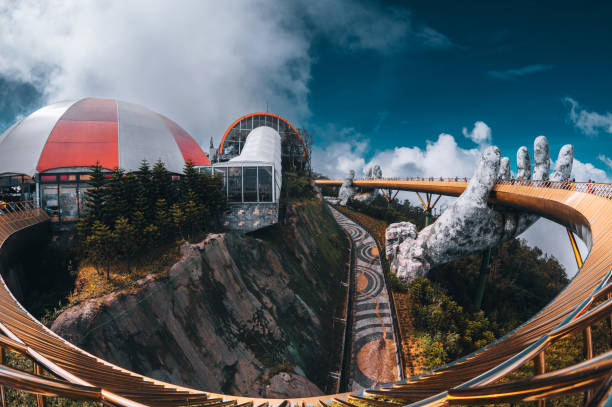 Da Nang city, Vietnam - November  18, 2022:Tourists walk on the Golden Bridge in Ba Na Hills, supported by a pair of giant hands. The bridge located 1,400 meters above sea level with hill scenery