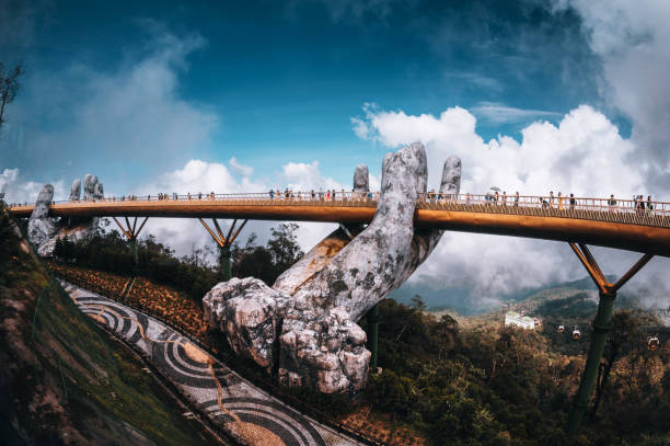 Da Nang city, Vietnam - November  18, 2022:Tourists walk on the Golden Bridge in Ba Na Hills, supported by a pair of giant hands. The bridge located 1,400 meters above sea level with hill scenery