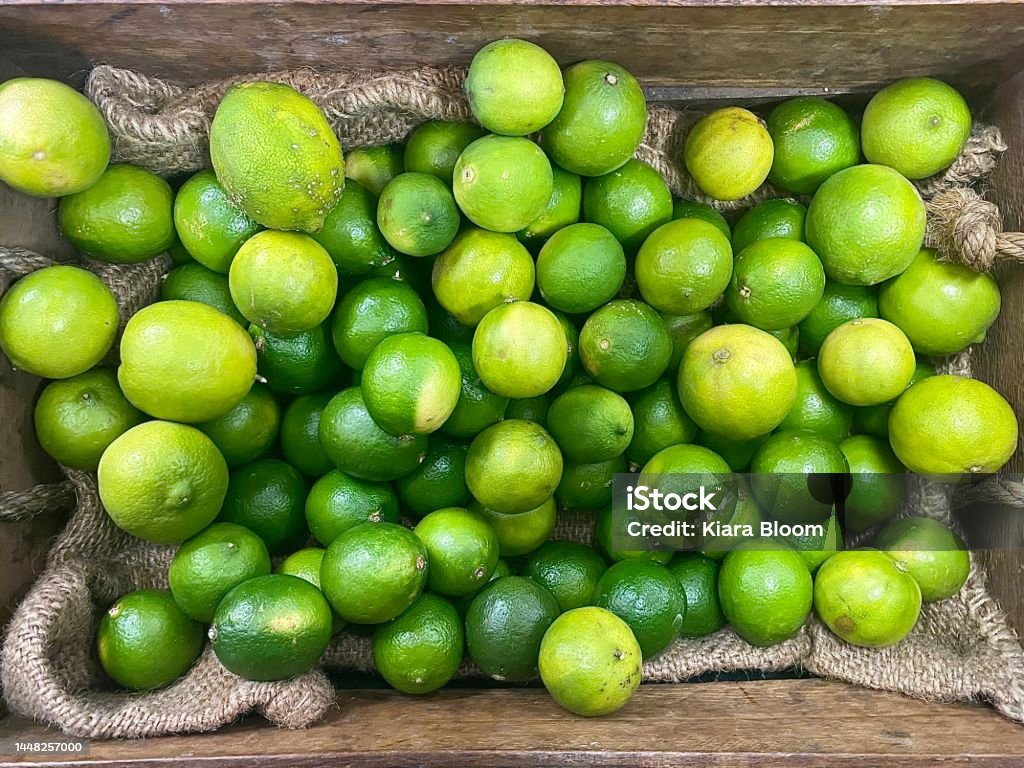 Organic Farm Fresh Market Limes Horizontal close up of bulk green citrus limes freshly picked from organic farm in wood box ready to eat Agriculture Stock Photo