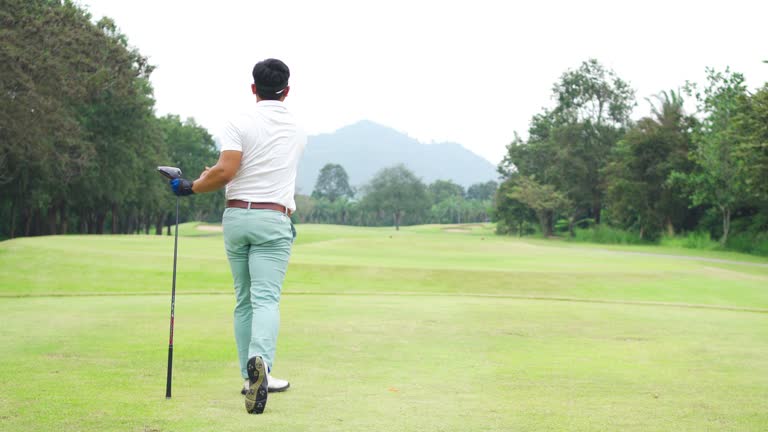 Male golf player taking a shot professional golf course.