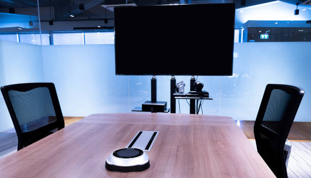 istock Wireless microphone portable on middle meeting table with blank screen television in Video conference meeting room 1448262428