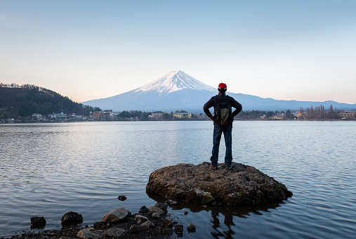 Man enjoying the view of sunrise over Mt Fuji, northern shore of Lake Kawaguchiko, Japan.