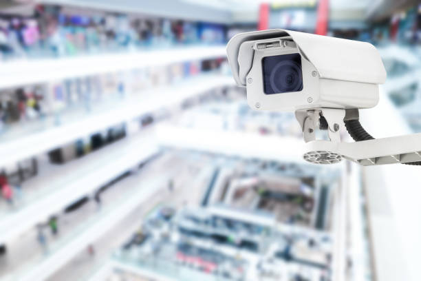istock Modern public CCTV camera with blur interior shopping mall background. Recording cameras for monitoring all day and night. Concept of surveillance and monitoring with copy space. 1448265297