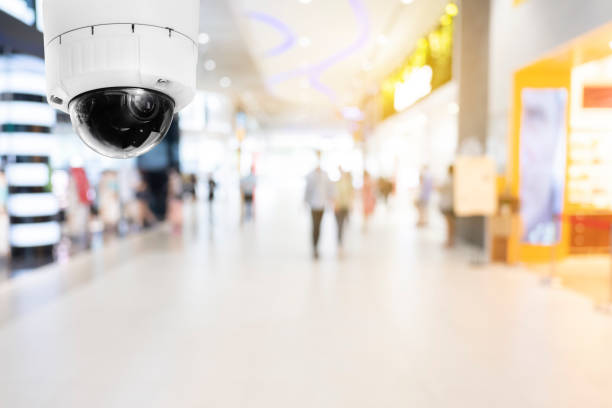 istock Modern public CCTV camera with blur interior shopping mall background. Recording cameras for monitoring all day and night. Concept of surveillance and monitoring with copy space. 1448265391