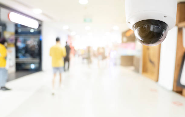 istock Modern public CCTV camera with blur interior shopping mall background. Recording cameras for monitoring all day and night. Concept of surveillance and monitoring with copy space. 1448265392