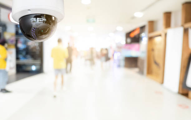 istock Modern public CCTV camera with blur interior shopping mall background. Recording cameras for monitoring all day and night. Concept of surveillance and monitoring with copy space. 1448265394