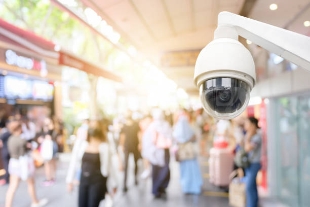 Modern public CCTV camera with blur crowd and shopping plaza background. Recording cameras for monitoring all day and night. Concept of surveillance and monitoring with copy space. Modern public CCTV camera with blur crowd and shopping plaza background. Recording cameras for monitoring all day and night. Concept of surveillance and monitoring with copy space. surveillance camera stock pictures, royalty-free photos & images