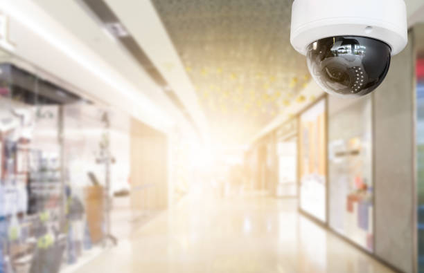 istock Modern public CCTV camera with blur interior shopping mall background. Recording cameras for monitoring all day and night. Concept of surveillance and monitoring with copy space. 1448265471