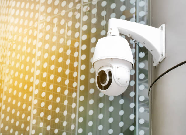 istock Modern public CCTV camera on wall with blur building background. Recording cameras for monitoring all day and night. Concept of surveillance and monitoring with copy space. 1448265504