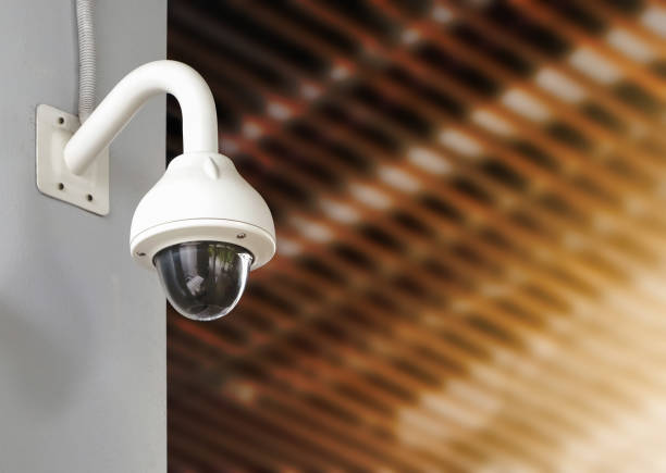 istock Modern public CCTV camera on wall with blur building background. Recording cameras for monitoring all day and night. Concept of surveillance and monitoring with copy space. 1448265506