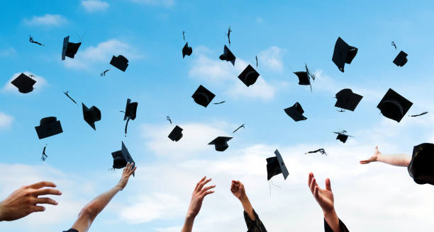 istock Graduating students hands throwing graduation caps in the air 1448272504