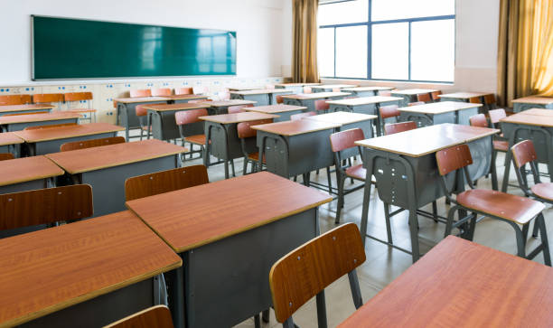 Empty classroom with desks, chairs and chalkboard stock photo