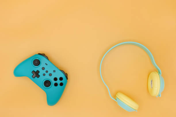 istock Green joystick gaming controller with green wireless headphone isolated on pastel yellow background, Video game console developed Interactive Entertainment 1448275942