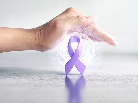 Hand cover over protect lavender color ribbon awareness symbolic for World Cancer Day or cancer awareness concept