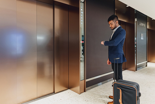 Young businessman looking at his watch near lift lobby