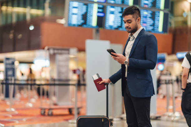 Young businessman waiting in the airport and texting with his phone stock photo