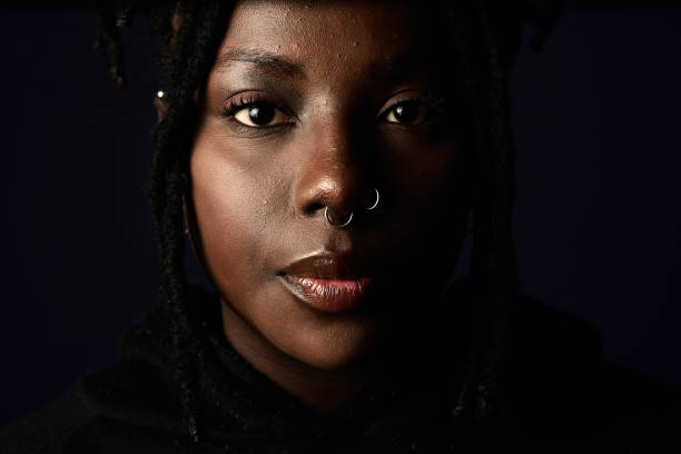 Close up portrait of an african woman with piercings Close up portrait of an alternative young african woman with piercings on the nose with black background color intensity stock pictures, royalty-free photos & images