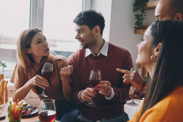 istock Happy young people drinking wine and talking while enjoying dinner at home together 1448284068