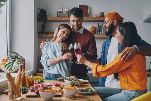 istock Group of beautiful young people toasting with wine and smiling while enjoying dinner together 1448284604