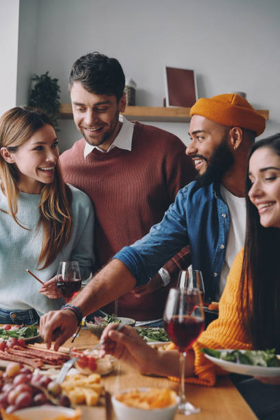 istock Group of young people talking and smiling while enjoying dinner at home together 1448284618