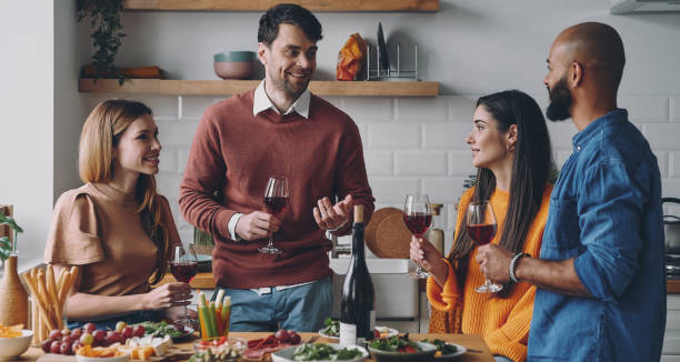istock Beautiful young people talking and smiling while enjoying dinner at home together 1448284821