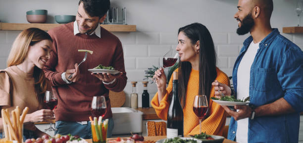 istock Group of young people talking and smiling while enjoying dinner at home together 1448284829