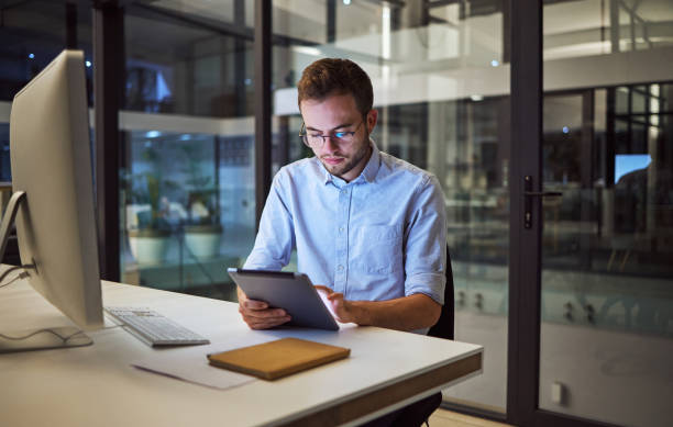 istock Business, communication and overtime, man with tablet and computer at desk. Late night at office, working on deal or internet project. Corporate worker in glasses, checking online financial report. 1448284909
