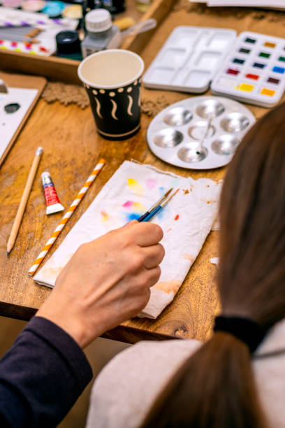 istock Middle-aged woman using watercolor brushes. 1448285122