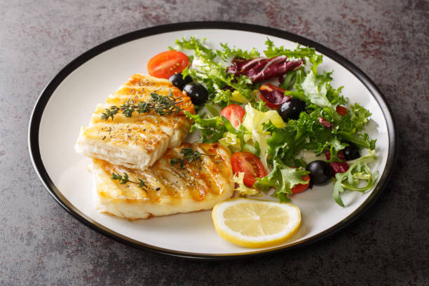 istock Spicy grilled cod fish fillet with fresh vegetable salad and leaf lettuce mix and lemon close-up in a plate. Horizontal 1448285123