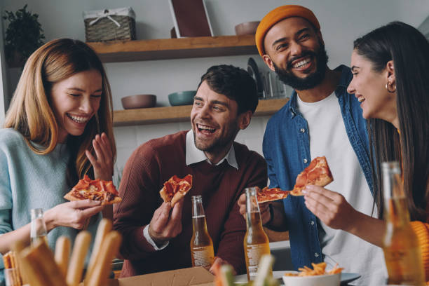 istock Cheerful young people eating pizza and laughing while enjoying fun time together 1448287608