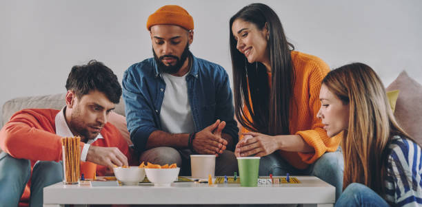 istock Beautiful young people playing board game while enjoying carefree time together 1448287632