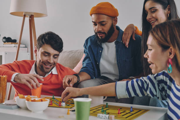 istock Cheerful young people playing board game while enjoying carefree time together 1448287746