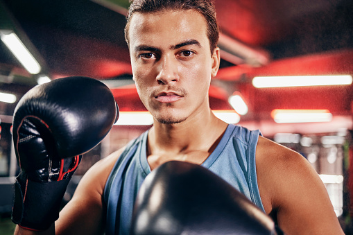 Fitness, boxing gloves and portrait of an athlete training for a fighting match or competition. Sports, motivation and man boxer in a gym to workout, exercise or practice for a martial arts fight.