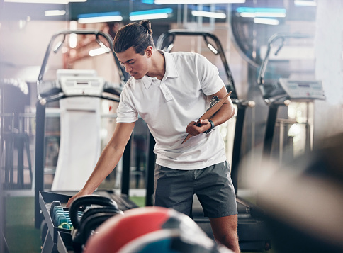 Gym, man and equipment clipboard with male manager checking weights in a health club for fitness. Exercise, workout and sports with a young man writing notes or list for a healthy, fit lifestyle