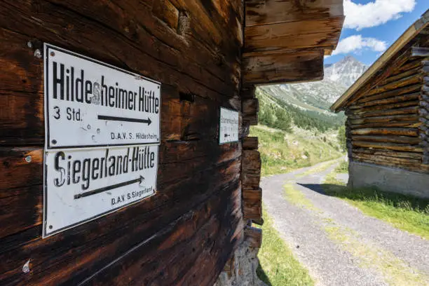 White signposts for directions to mountain huts in the Ötztal Alps at wooden wall of an alpine barn in the Windach valley, Sölden, Austria
